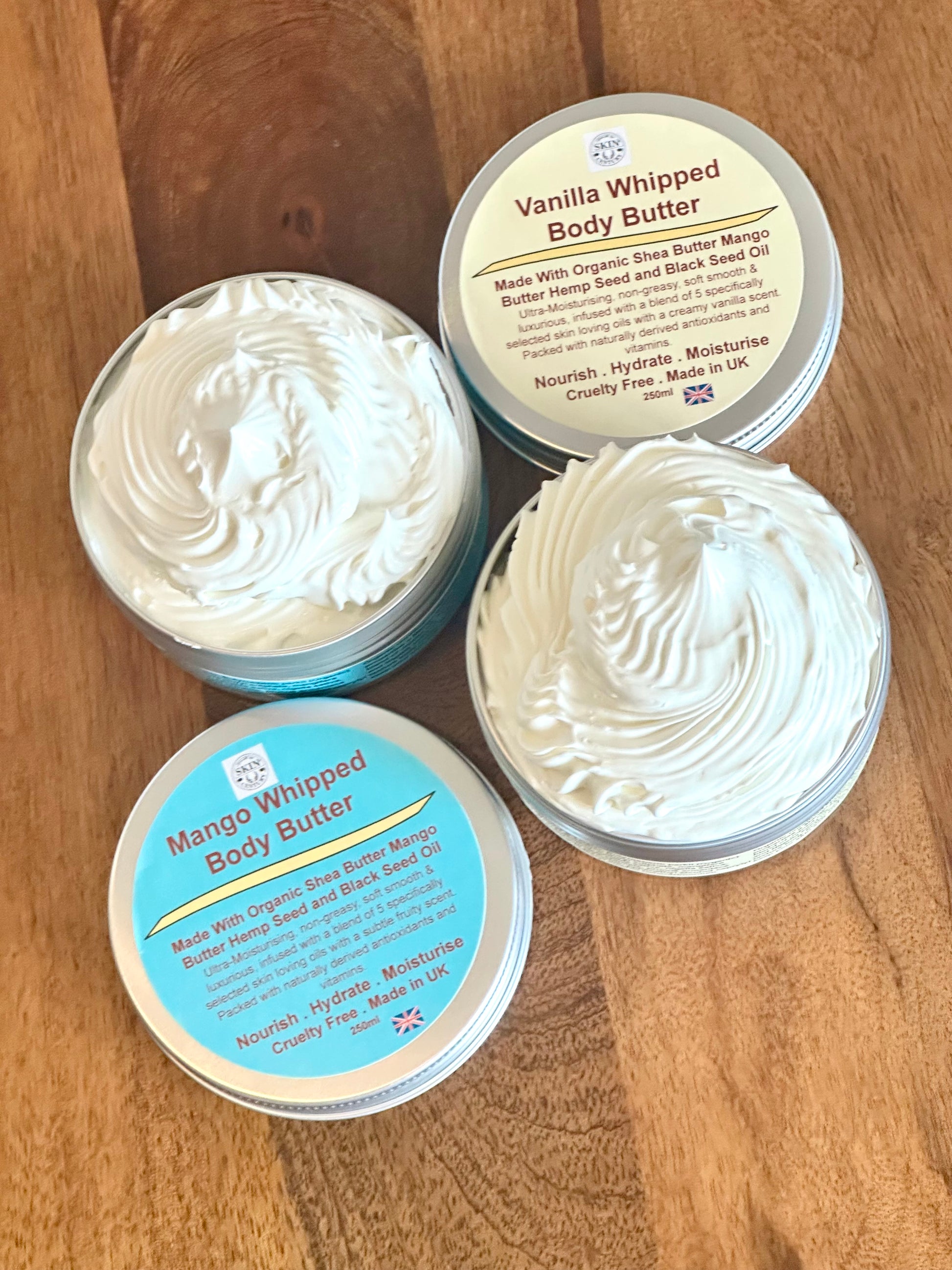 Two containers of Vanilla Whipped Body Butter on a wooden surface